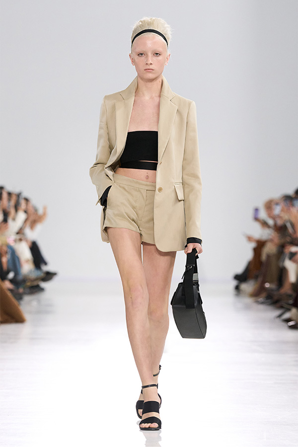 Défilé Max Mara Printemps Été 2026 : look beige avec blazer, short et sac noir.