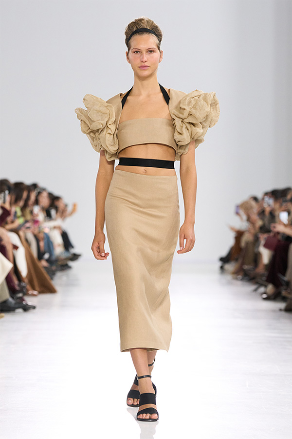 Défilé Max Mara Printemps Été 2026 : look beige avec haut à bride à volants et jupe coupe ajustée.