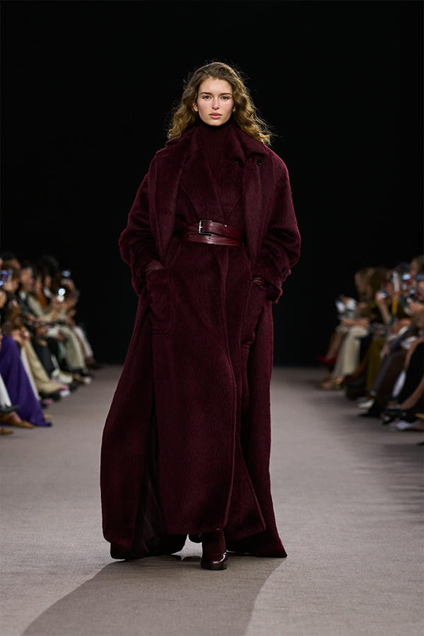 Défilé Max Mara Automne Hiver 2025 : look cerise avec manteau long, manteau sans manche, ceinture, leggings et escarpins Mary Jane.